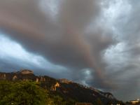 Leuchtender, dunkler Wolkenstreifen über den Bergen